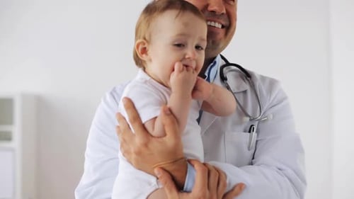 Happy Doctor Holds Infant Patient in Examination Room