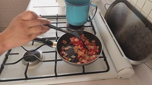 Person Cooking Ingredients in a Pan on Stove