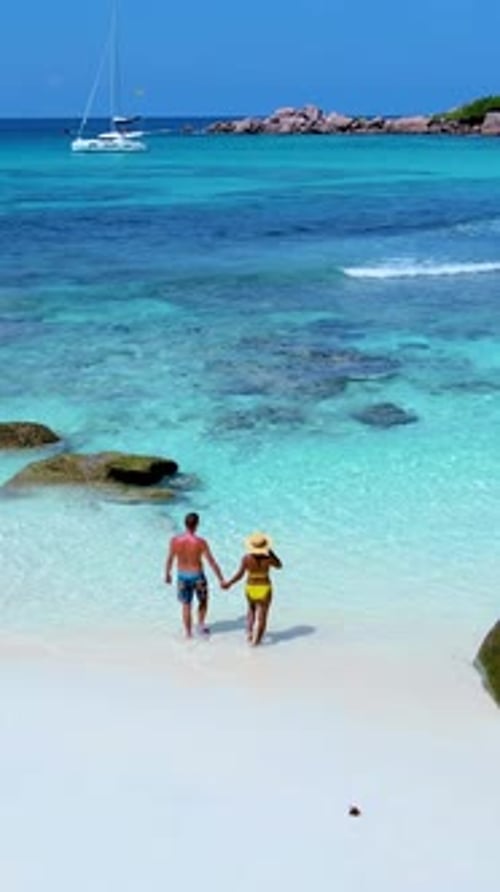 Enjoying a Sunny Beach Stroll in the Stunning Waters of Seychelles Together