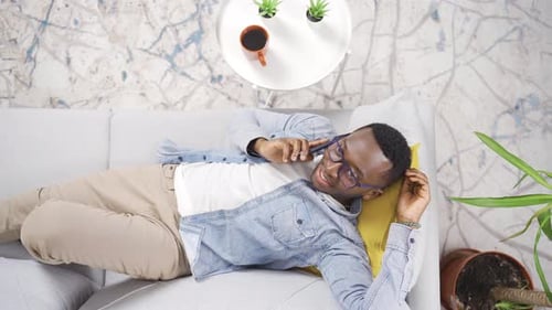 Top view of young African man with glasses talking on the phone.