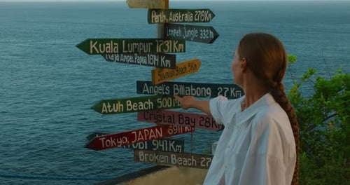 Woman pointing at destination sign on tropical beach