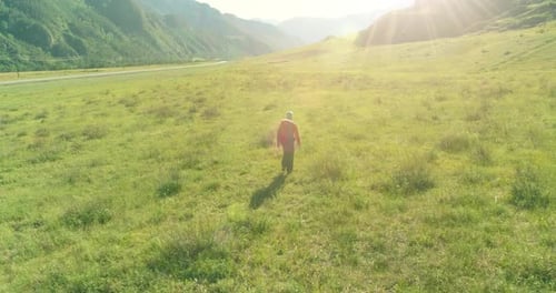 Flight Over Backpack Hiking Tourist Walking Across Green Mountain Field Huge Rural Valley at Summer