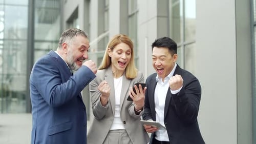 group of colleagues fellow employees read good news looking at smartphone. Happy team rejoices about