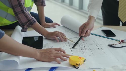 Architects Collaborating on Building Blueprint in Office