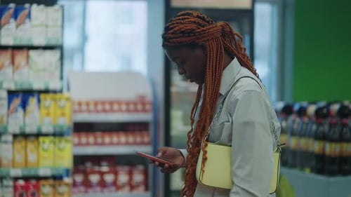 Black Woman Shopping Healthy Food in Supermarket Background Female Buy Products Using Digital Gadget