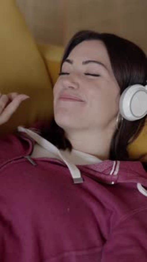 Woman Listens to Music, Relaxing on Couch
