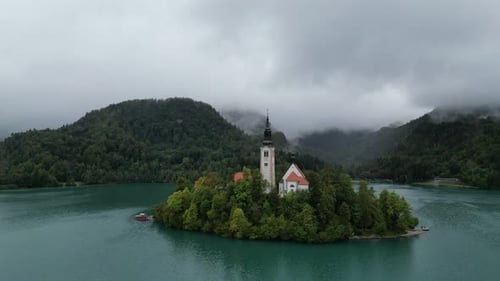 Lake Bled Slovenia drone aerial view low clouds covering wooded hills in background