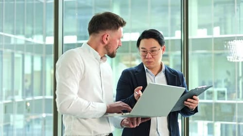 Businessmen Collaborating on a Laptop in a Modern Office