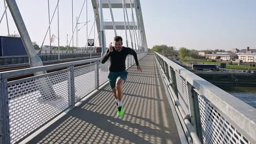 Male runner running on the bridge in the city during day.