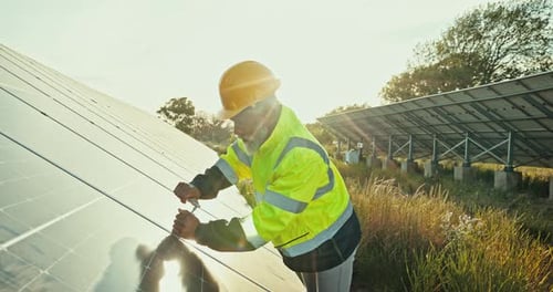 Worker Tightens Solar Panel Bolt in Rural Field