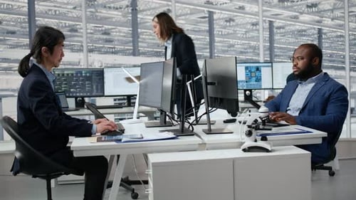 Man Examining Microchip Circuit Layouts on Computer Monitor in Factory RD Office