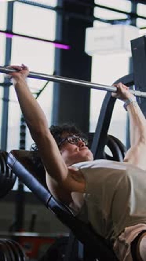 Toned Man Doing Bench Press in Gym