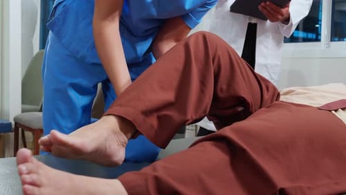 Nurse physiotherapy with elderly patient while stretch leg in hospital.