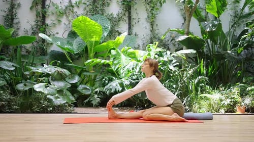 Woman in focused lotus position in green garden