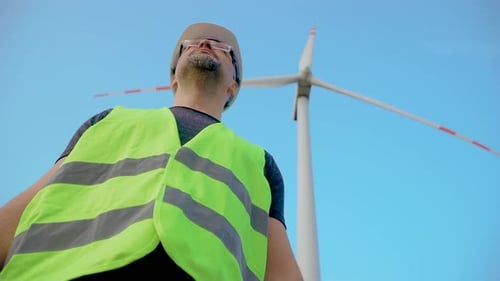 Make Renewable Energy Engineer in Workwear and Hard Hat Standing at Windturbine Farm in Front of