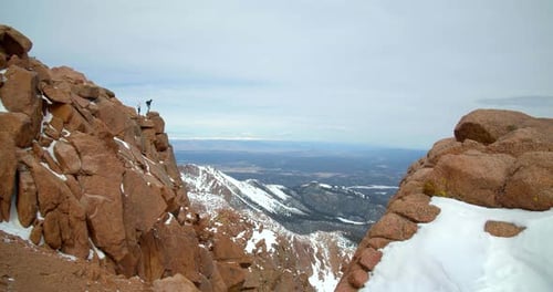 Couple atop rocky mountains embrace adventure close up aerial view