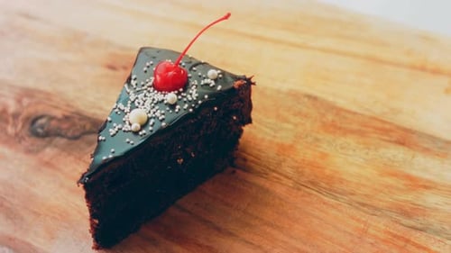 Chocolate Cake Slice with Cherry on Cutting Board