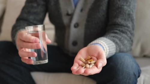 Close Up of Person Holding Pills and Water