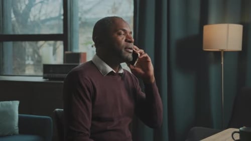 Worried man talking on phone in living room