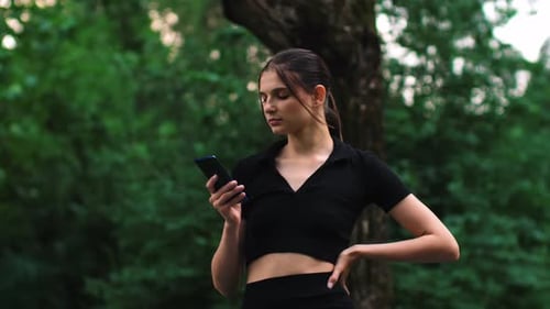 Woman Using Phone in Green Park Setting