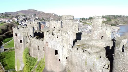 Medieval Conwy castle Welsh market town ruins aerial view historical harbour close up orbit left