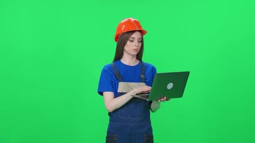 Portrait of a Focused Woman Worker in a Uniform and Protective Helmet Engineer Stands and Uses a