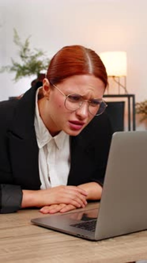 Junge Geschäftsfrau reibt müde Augen und setzt dann eine Brille auf und freut sich über die klare, lebendige Laptop-Ansicht
