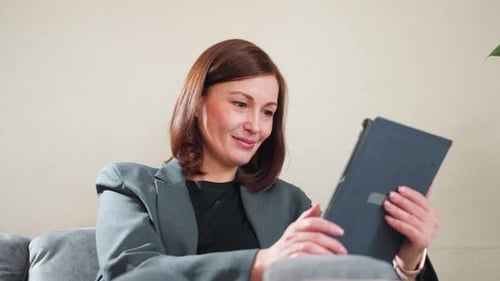 Woman Using Tablet Device Sitting Indoors