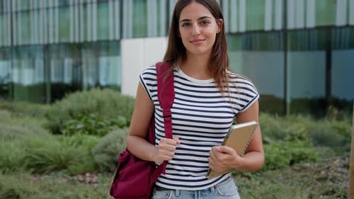 Retrato de uma jovem estudante hispânica na escola universitária segurando livros didáticos sorrindo
