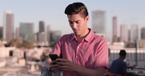 Man using phone on city rooftop at daytime