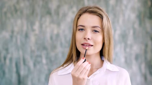 Woman Applying Lip Gloss for Beautiful Makeup Look