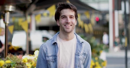 Smiling young man in city setting looks at camera