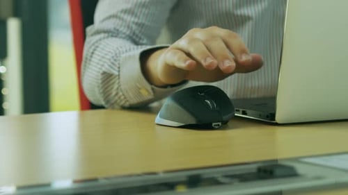 Kaukasischer Mann sitzt am Schreibtisch und arbeitet aus der Ferne, benutzt Laptop und Maus