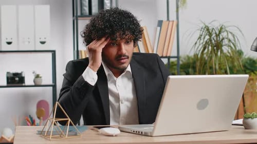 Frustrated Man on Video Call at Office Desk
