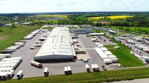 Aerial view of a semi trucks with cargo trailers standing on warehouses ramps for loading/unloading