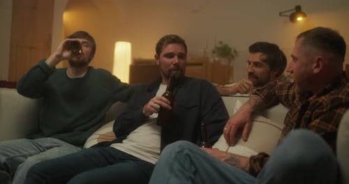 Four Young Men Drinking Beer Together at Home