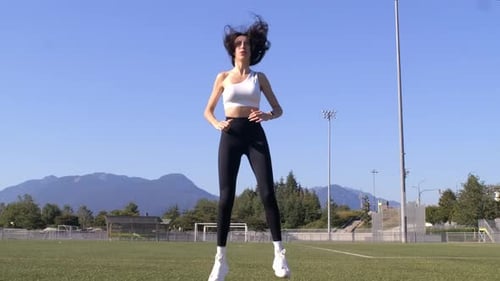 Fit Woman Exercises at Sports Field - Jump Squat Slomo - Sunny Day