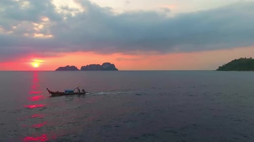 A low aerial view of longtail thai boat in sunset. Boat fast moving