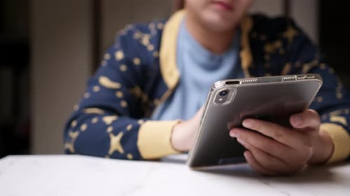 Close-up of an individual scribbling and writing some notes using a portable electronic tablet and a