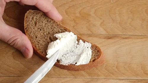 Spreading Cream Cheese on Rye Bread Slice