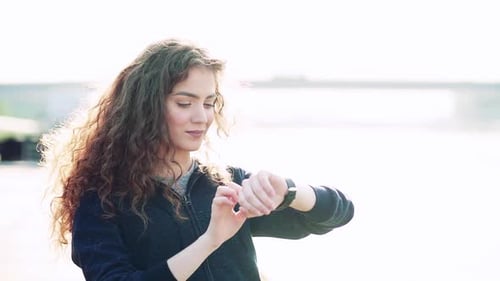 Frau steht draußen in der Stadt und benutzt Smartwatch.
