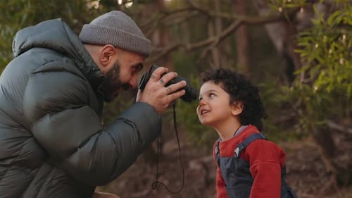 Un père et son fils ludiques utilisant des jumelles dans la forêt ont partagé leur curiosité et leur joie