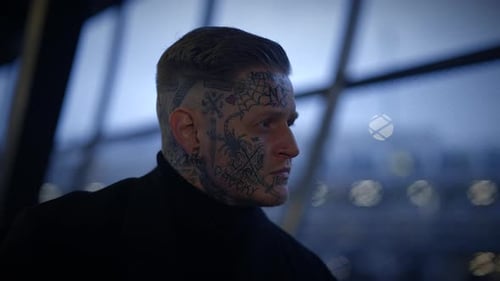Stylish Man with Tattoos Leaning Against Modern Structure