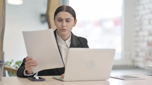 Woman Analyzing Documents in Modern Office Setting