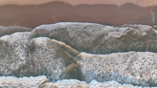 An aerial view of the wide beach and waves. Seascape from a drone during sunset.