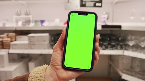 Close Up Hand Use Mobile Smartphone with Vertical Green Screen in Department Store Blurred