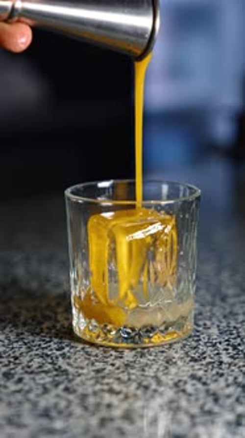 Pouring Cocktail into Glass with Ice Cube