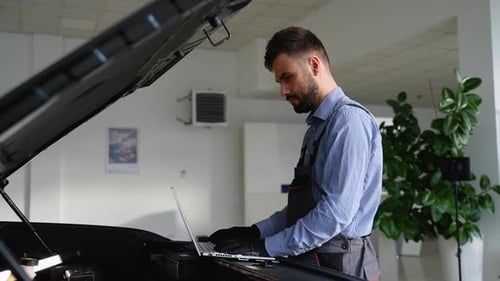 Mecánico realizando diagnósticos de automóviles con una computadora portátil en el taller