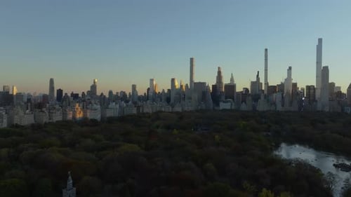 Aerial View of Central Park While Sunlight Illuminates Modern and Classic Skyscrapers in a Lively