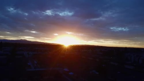 Sonnenstrahlen durch Wolken über dem Stadtbild, Drohnenschuss.